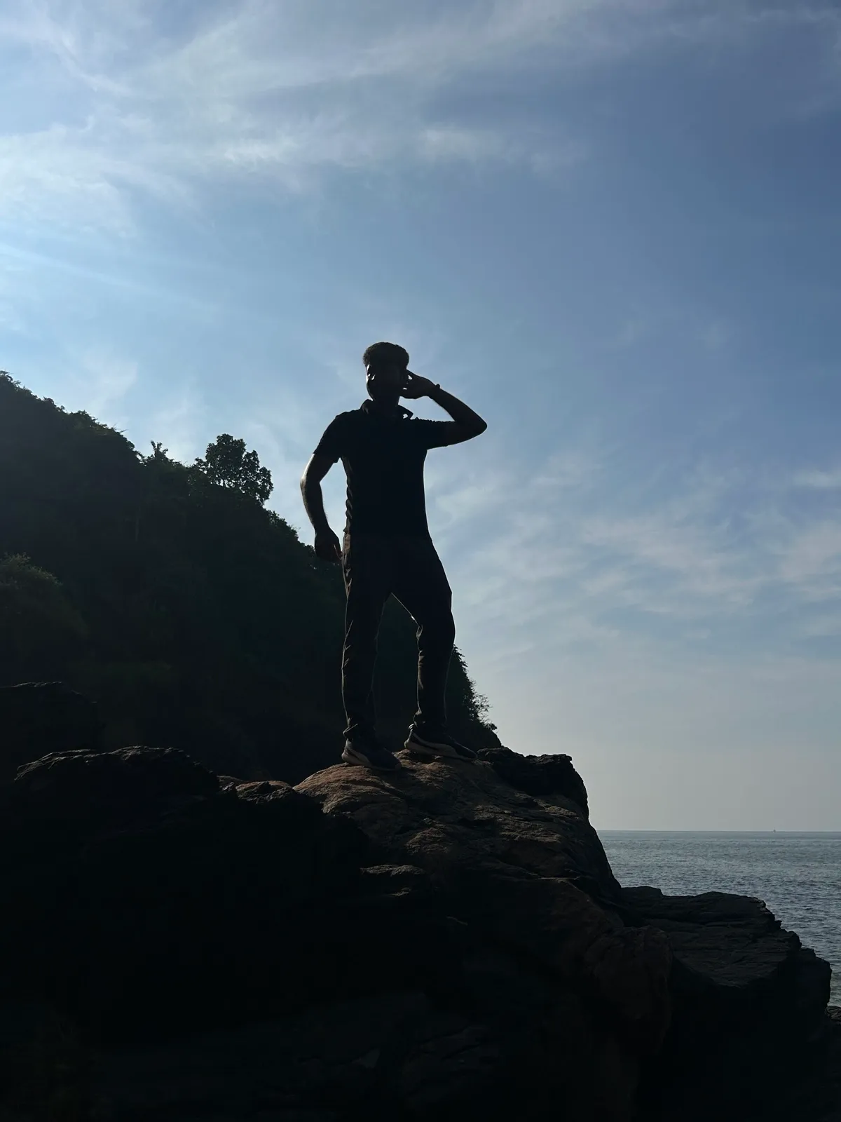Silhouette standing on a rock by the sea